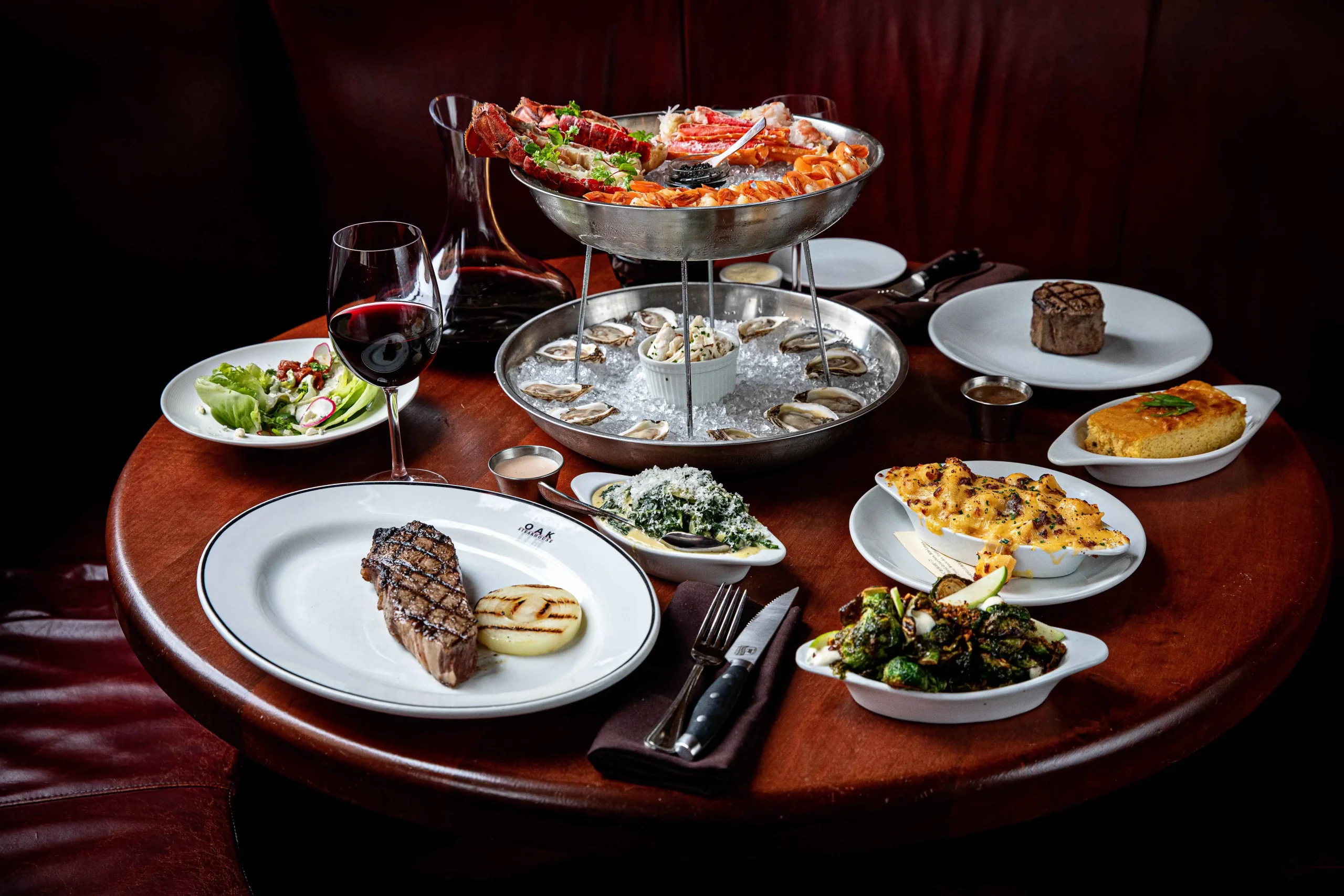 A spread of steakhouse classics including a selection from the raw bar and sides like creamed spinach and macaroni and cheese at Oak Steakhouse in Charleston