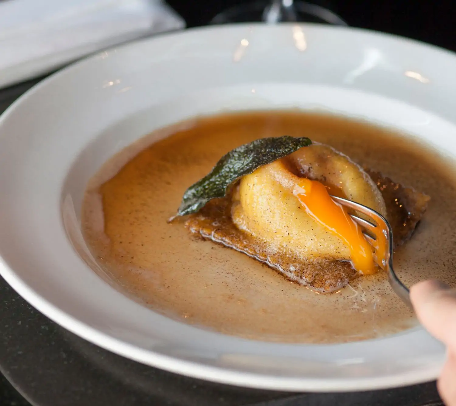 featured image Credit Osteria Mozza.jpeg A fork is piercing a ravioli filled with a bright yellow yolk, which is surrounded by a rich brown sauce and a sage leaf at Osteria Mozza, one of the best restaurants in Melrose Los Angeles, available on OpenTable.