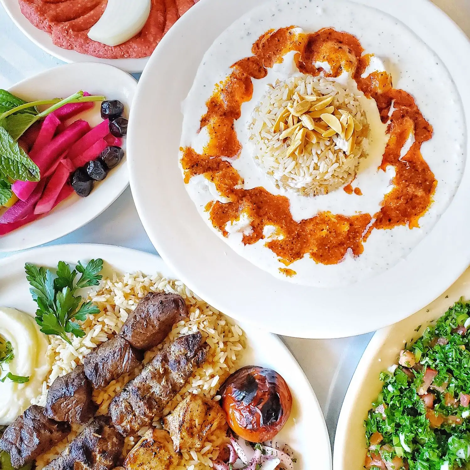 Credit Marouch A table with a variety of Middle Eastern dishes, including grilled meats, rice, salads, and dips at Marouch, one of the best Lebanese restaurants Los Angeles has—available on OpenTable.