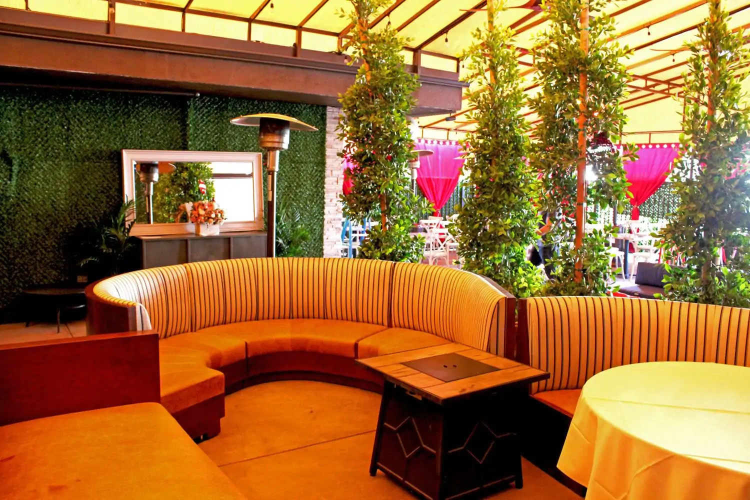 Credit Elena_s Estiatorio.jpg An outdoor patio dining area with a curved banquette seating area decorated with greenery and colorful accents. There are tables with white tablecloths and a fire pit in the center at Elena’s Estiatorio, one of the best Mediterranean restaurants in Los Angeles, on OpenTable.