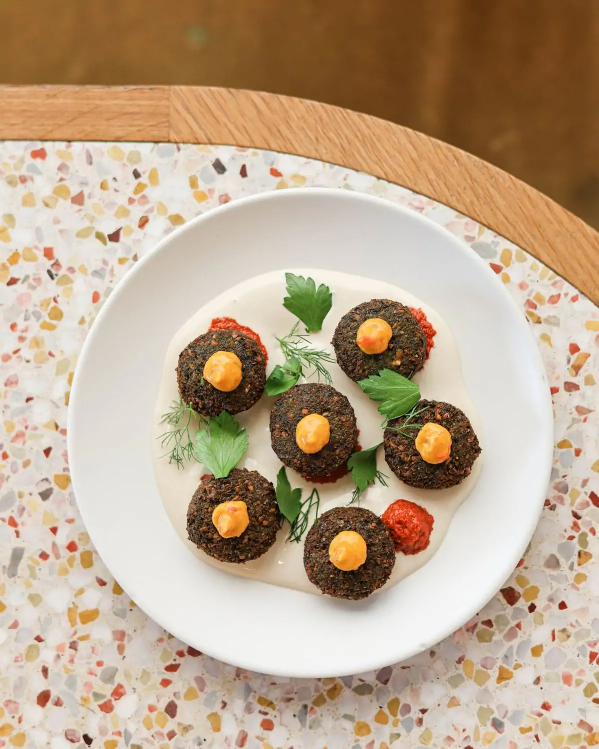 featured image Credit Saffy_s.jpg A plate of falafel balls drizzled with a creamy sauce and topped with a dollop of a bright orange sauce and fresh parsley atop a white plate at Saffy’s in Los Angeles, available on OpenTable.