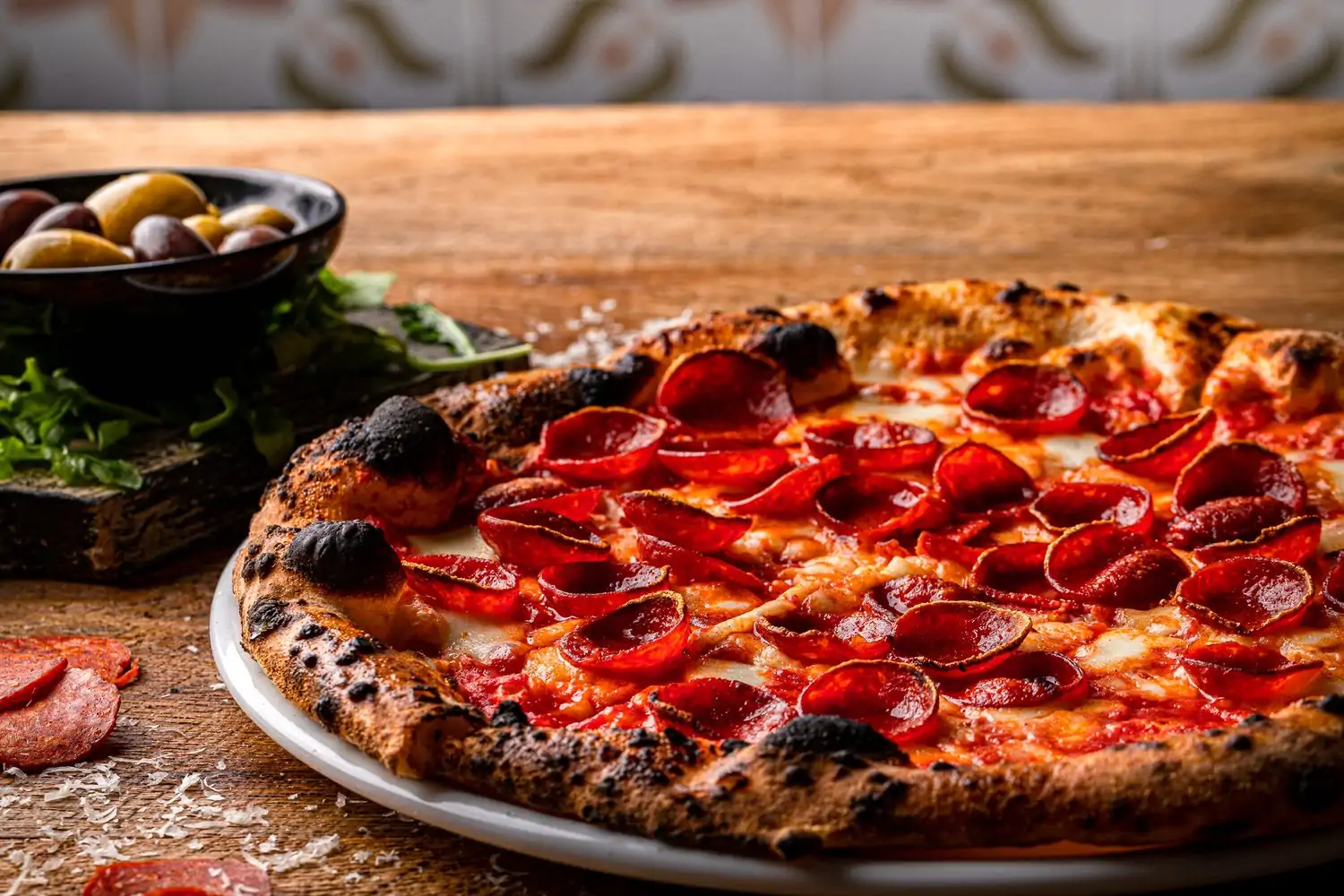 A bowl of olives and a pepperoni pizza at Sunnyside Pizzeria, one of the best family restaurants in Atlanta. Reserve on OpenTable.