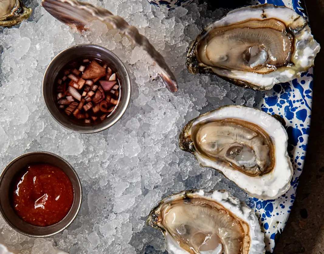 Three oysters on ice next to some mignonette at Charleston restaurant NICO Oysters + Seafood