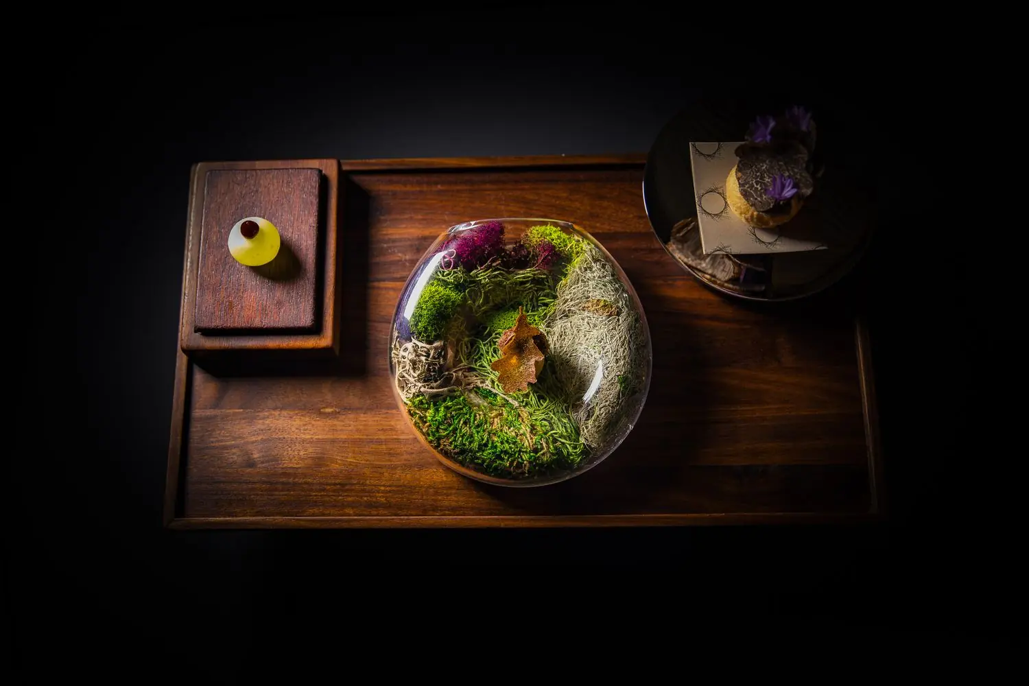 Composed dishes on a wooden table at Atelier Crenn in San Francisco