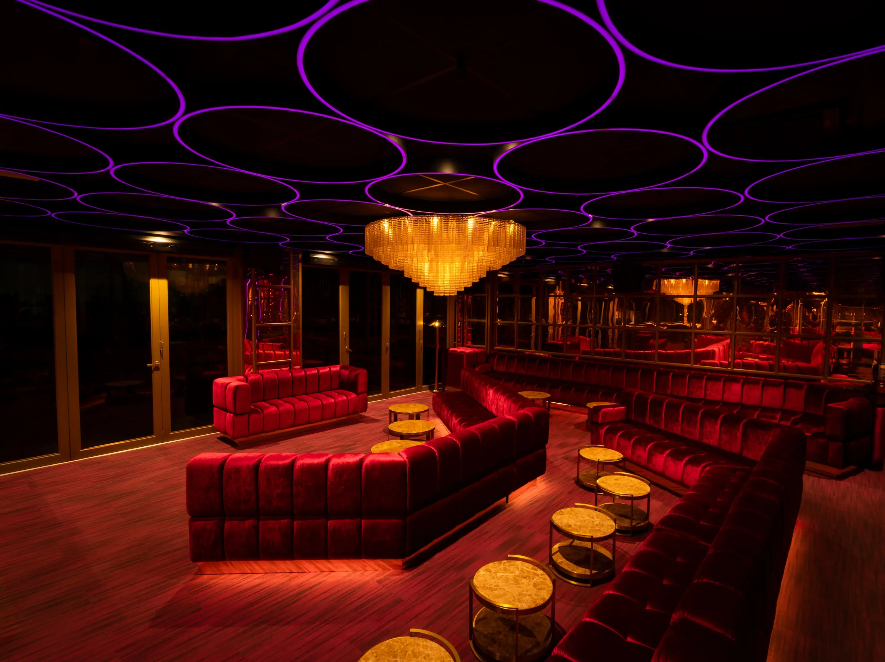 Red velvet seating with purple lights above at Elixir in Miami Beach