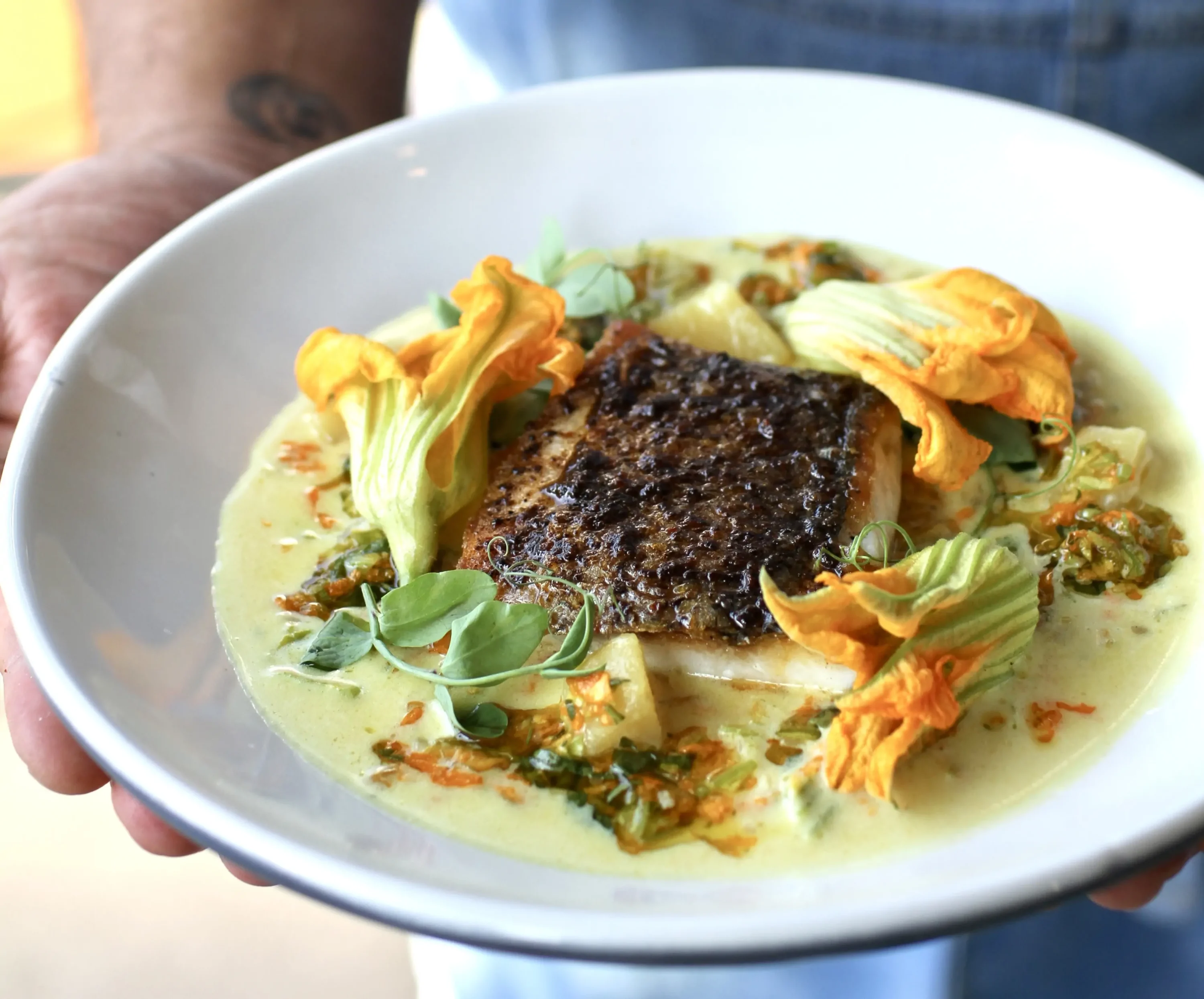 A grilled fish dish in a sauce with squash blossoms at Botanica in Los Angeles