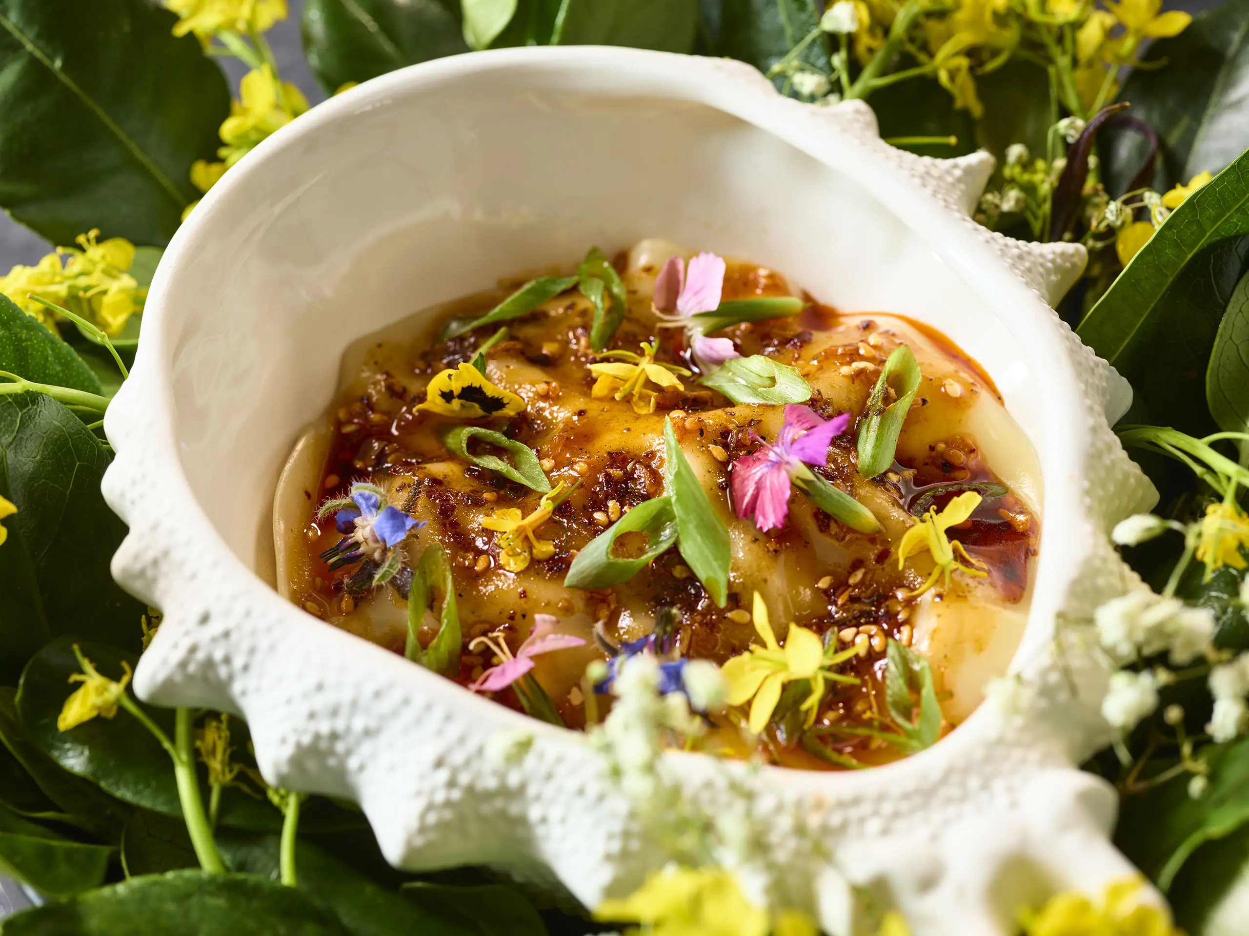 Crab dumplings in a conch shell topped with spring onions and edible flowers at Vinyl Room in Las Vegas
