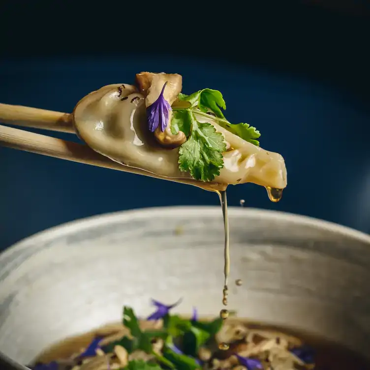 A diner eating gyoza with chopsticks at The Ivy Asia, one of the best Asian restaurants in London