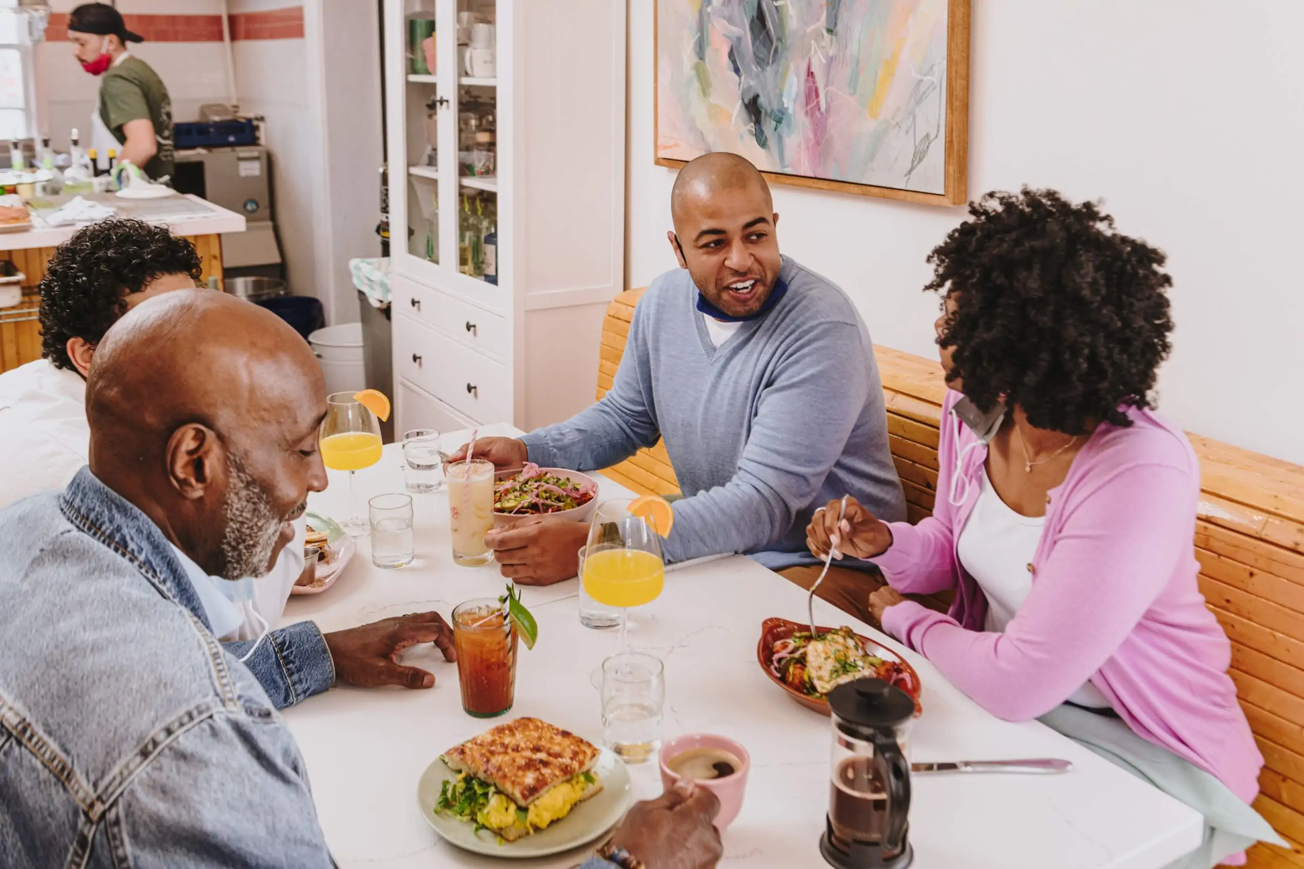 A restaurant scene depicts a group of 5 diners having a conversation while enjoying a meal