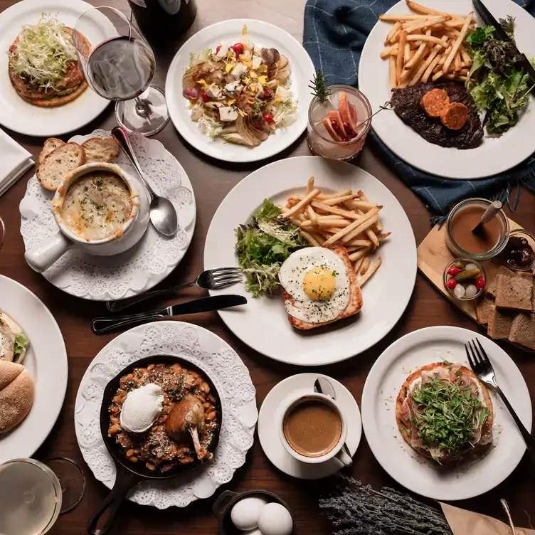 mereon-bistro2 A top-down view of a table laid with multiple dishes, including a croque madame and steak frites at Merèon Bistro, one of Vancouver’s best French restaurants.