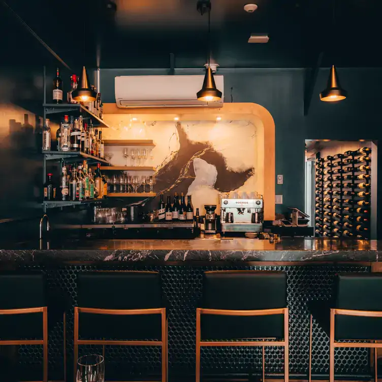 atelier-by-matt-jackson2 The bar at Atelier by Matt Jackson lined with stools on one side and shelves of spirits and wine on the other.