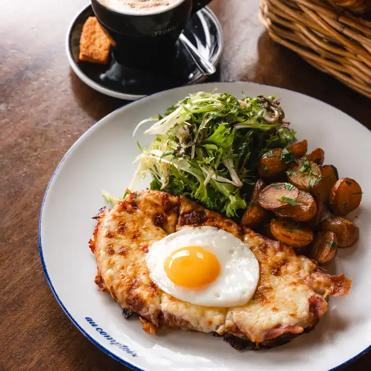 au-comptoir3 A dish topped with cheese and a fried egg served alongside vegetables at Au Comptoir.