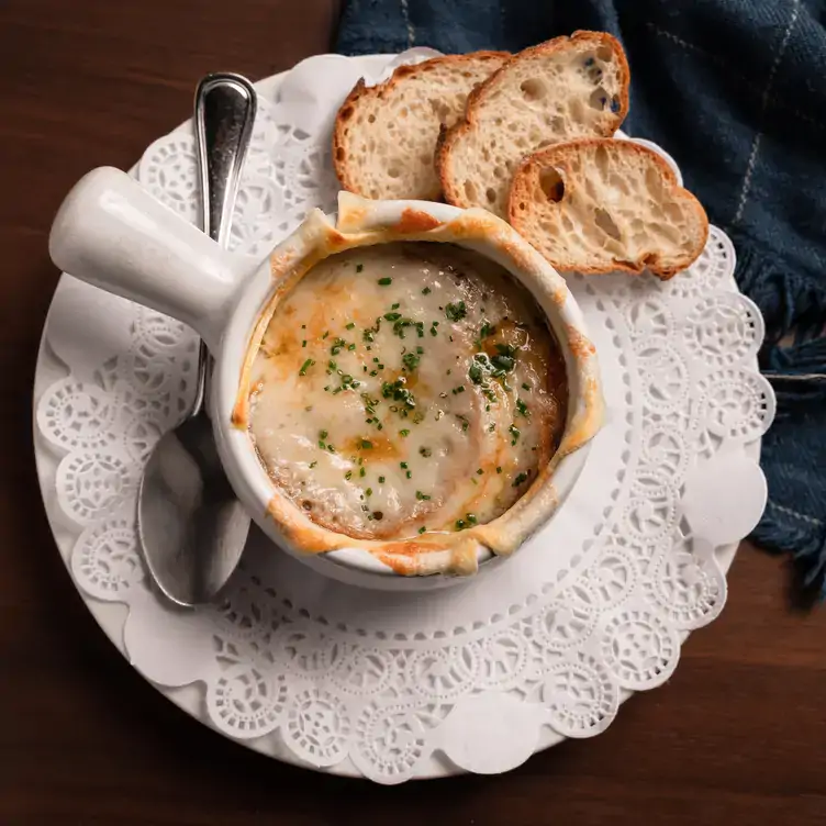 1-featured_-mereon-bistro A small dish topped with melted cheese served alongside bread at Merèon Bistro, one of the best French restaurants in Vancouver.